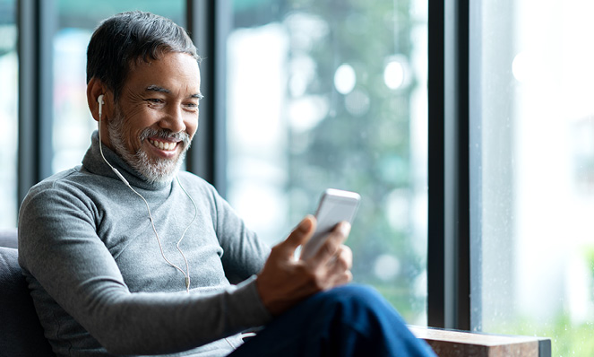 older-man-smiling-looking-at-phone-with-earbud