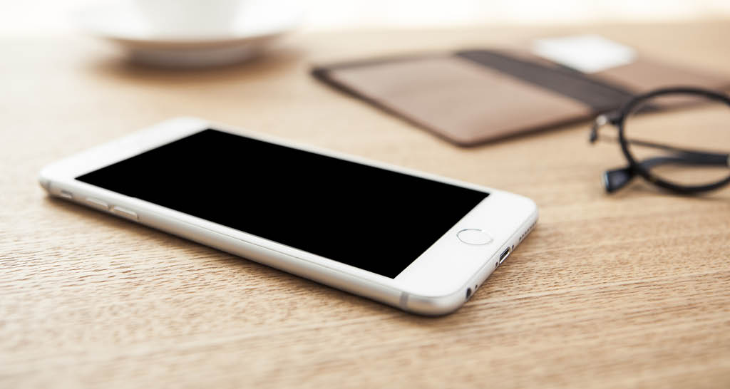 white-cell-phone-laying-on-wood-table-black-frame-glasses